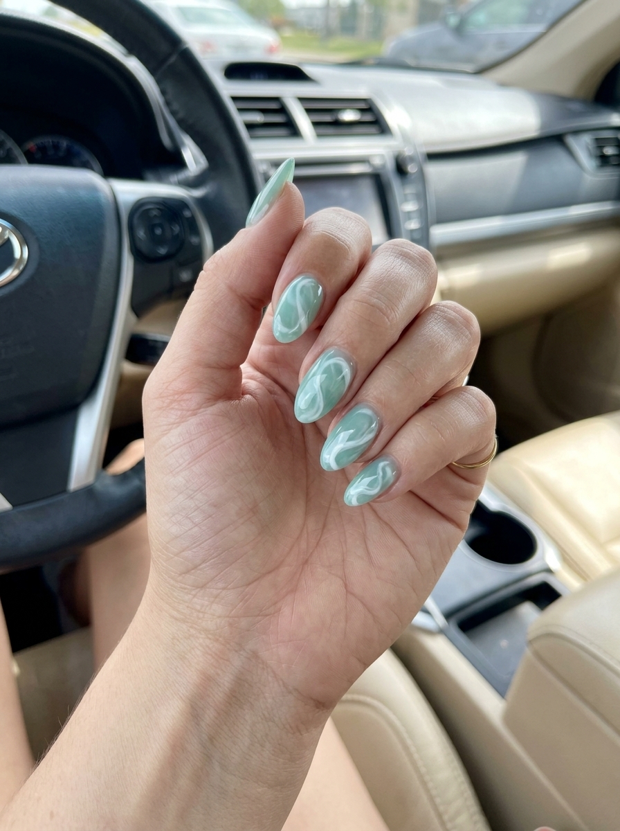 Seafoam green jelly almond nails with opaque milky white swirls. Tropical summer nails almond 2026.