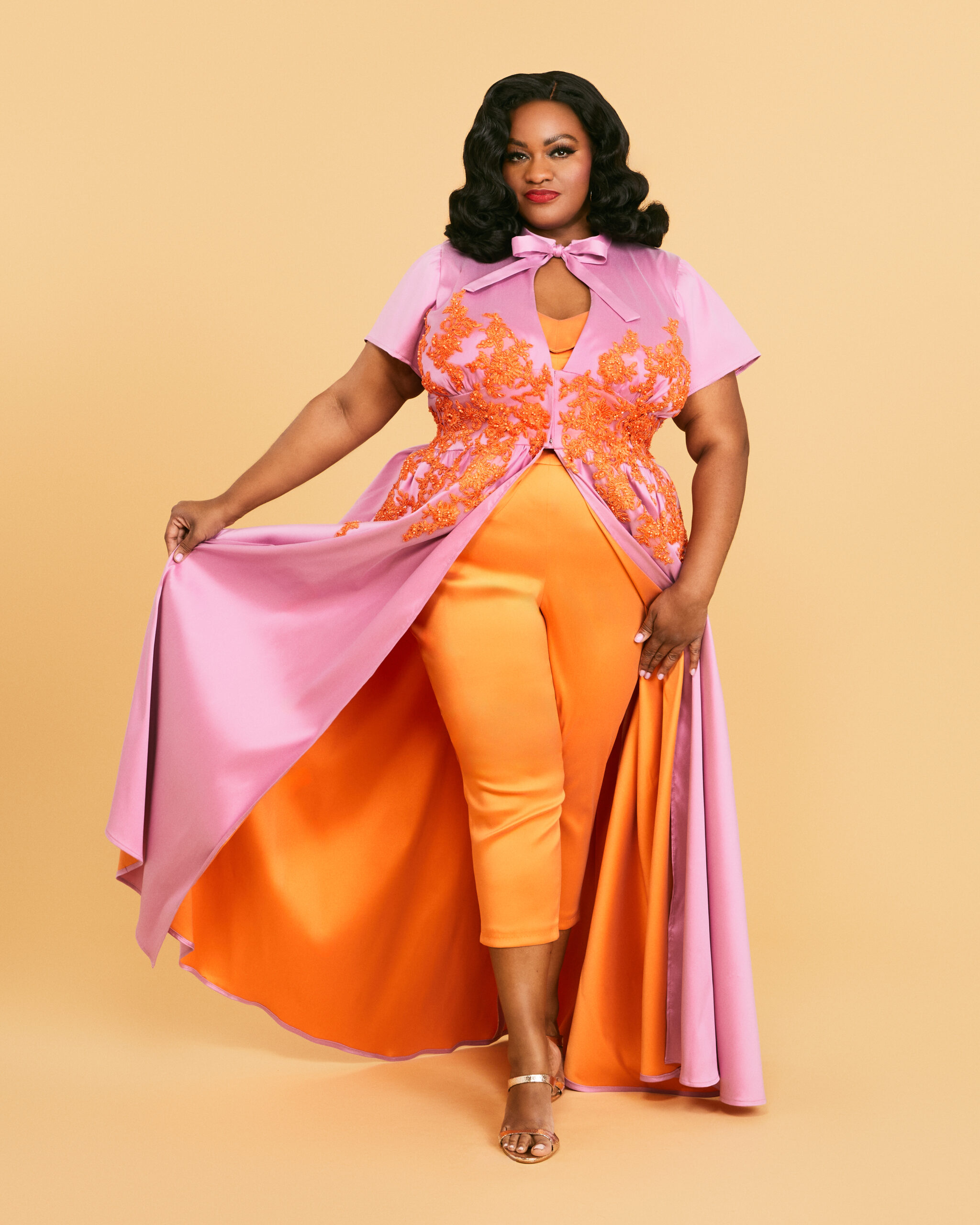 Orange Jumpsuit with Dramatic Pink Cape for a Striking Hostess Orange Jumpsuit with Dramatic Pink Cape for a Striking Hostess — Hostess Outfits 2027