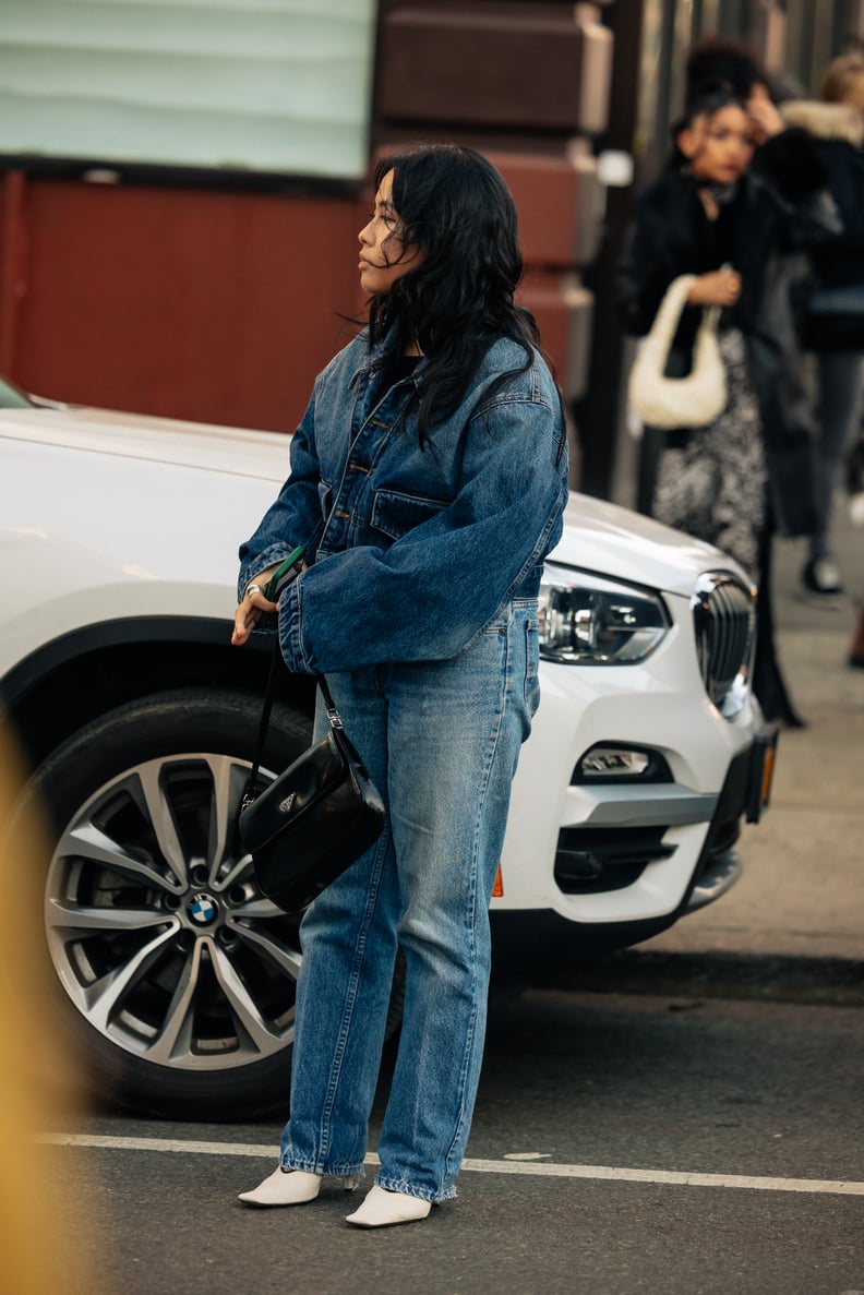Chic Drape: Denim Jacket Styled Over Shoulders with White Boots — Denim Jacket Outfits 2027