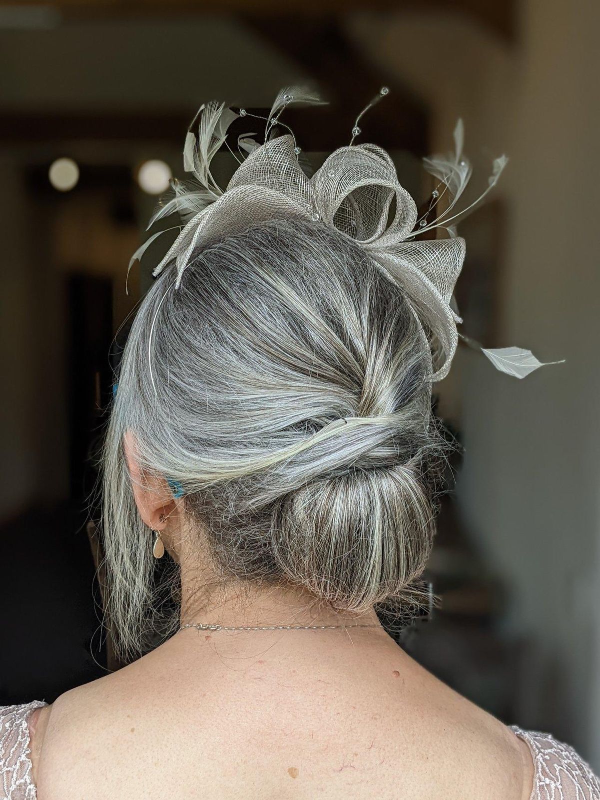 Grey Low Bun With Feathers Grey Low Bun With Feathers — Church Wedding Hairstyles 2027